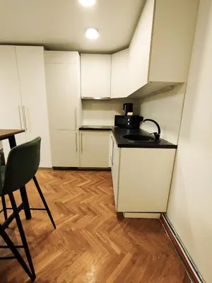 a small kitchen with white cabinets and a table at Cozy Noko Apartments in Kaunas