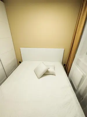 a white bed with a pillow sitting on it at Cozy Noko Apartments in Kaunas