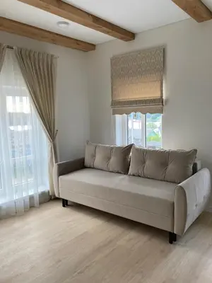 a couch in a living room with two windows at Apartamentai Domus Antiqua in Zarasai