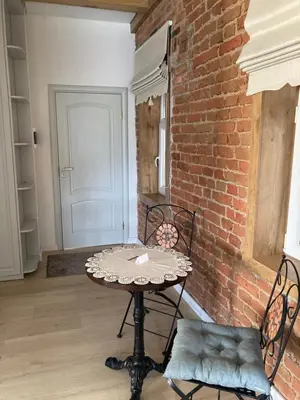 a table and chairs in a room with a brick wall at Apartamentai Domus Antiqua in Zarasai