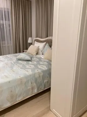 a bedroom with a bed with white sheets and pillows at Apartamentai Domus Antiqua in Zarasai