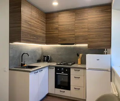 a kitchen with white appliances and wooden cabinets at Cozy Studio Apartment in the City Center in Šiauliai