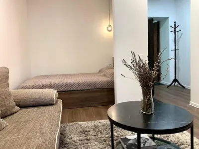 a living room with a table and a bed at Cozy Studio Apartment in the City Center in Šiauliai