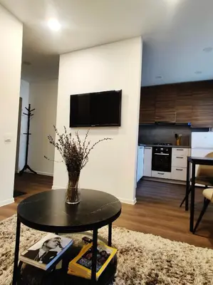 a living room with a table and a kitchen at Cozy Studio Apartment in the City Center in Šiauliai