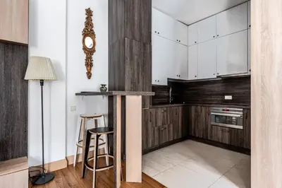 a kitchen with white cabinets and a clock on the wall at Gusto Apartment in Kaunas