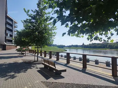 a row of benches on a walkway next to a river at Kaunas Castle Apartment in Kaunas