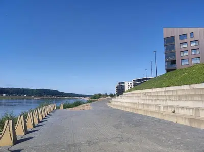 a walkway next to a river next to a building at Kaunas Castle Apartment in Kaunas