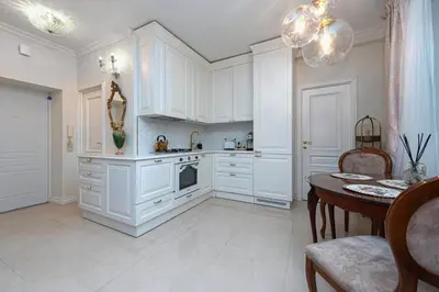 a kitchen with white cabinets and a dining table at Elegant Old Town Apartment with Terrace & Parking in Vilnius
