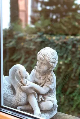 a white statue of a child holding a bird at Elegant Old Town Apartment with Terrace & Parking in Vilnius