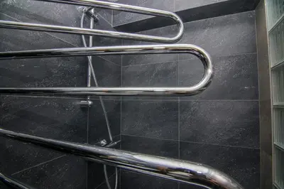 a bathroom with black tiles and stainless steel railings at Modernios klasikos studija in Kaunas