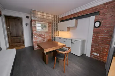 a kitchen with a wooden table and a brick wall at Modernios klasikos studija in Kaunas