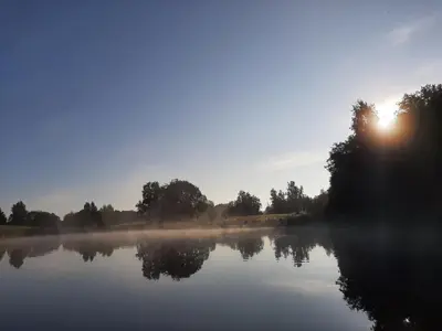 a misty lake with the sun in the background at Terra Gratia - namukas Išminčius in Nemeikšiai