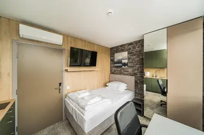 a small bedroom with a bed and a desk and a door at Zaliakalnio Terasos apartamentai 2 in Kaunas