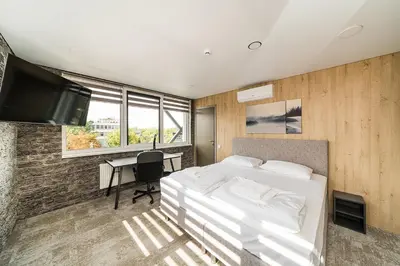 a bedroom with a bed and a desk and a tv at Zaliakalnio Terasos apartamentai 2 in Kaunas