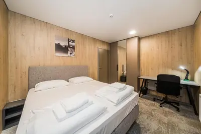a bedroom with a bed with white pillows and a desk at Zaliakalnio Terasos apartamentai 2 in Kaunas
