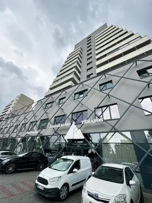 two cars parked in front of a large building at Zaliakalnio Terasos apartamentai 2 in Kaunas