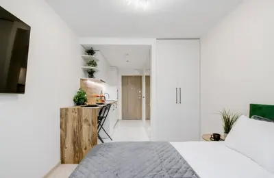 a white bedroom with a bed and a kitchen at Zveryno apartment in Vilnius
