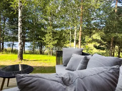 a couch sitting next to a table and trees at IVIS House Lakeside Retreat in Vilnius in Vilnius