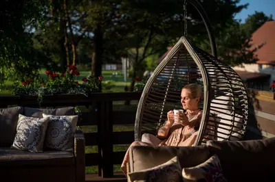 a woman sitting in a swing with a cup of coffee at Shanti Resort - Retreat & Wellness Center in Sarboriškės I