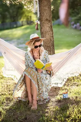 a woman sitting in a hammock reading a book at Shanti Resort - Retreat & Wellness Center in Sarboriškės I