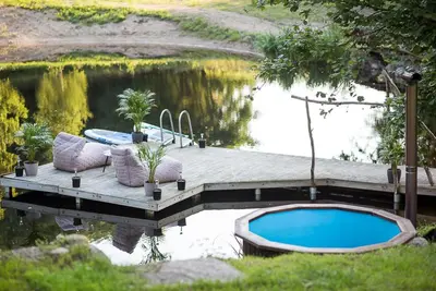 a dock with a swimming pool next to a body of water at Shanti Resort - Retreat & Wellness Center in Sarboriškės I