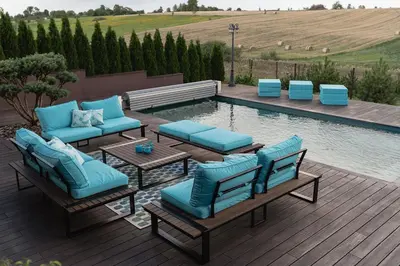 a patio with blue lounge chairs and a pool at LAGUNA SPA šeimos poilsio namai in Geniai