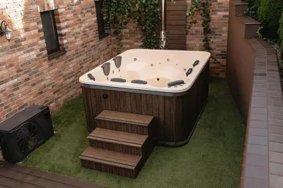 a bath tub sitting on the grass next to a building at LAGUNA SPA šeimos poilsio namai in Geniai