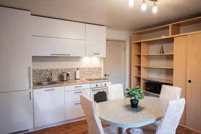 a kitchen with white cabinets and a table and chairs at Angelica Apartment in Vilnius