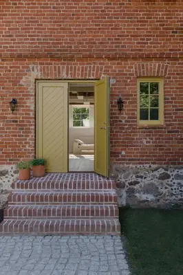 a brick building with a yellow door and stairs at Aštriosios Kirsnos dvaras in Aštrioji Kirsna