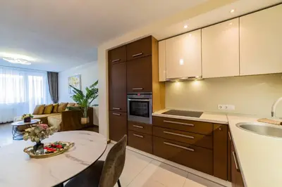 a kitchen with wooden cabinets and a table in a room at ASTeS Apartments in Šiauliai