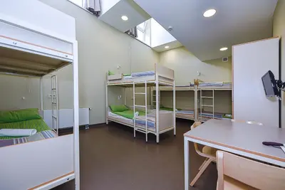 a room with bunk beds and a table and a desk at Nykščio Hostel in Anykščiai