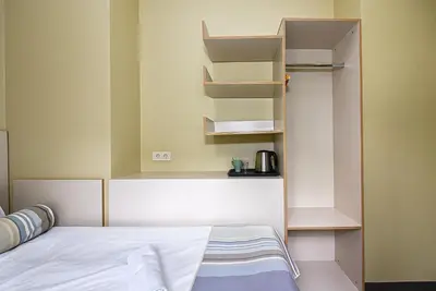 a small bedroom with a bed and shelves at Nykščio Hostel in Anykščiai