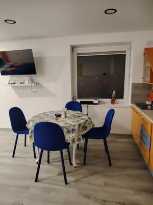 a dining room with a table and blue chairs at Jolsva in Rokiškis