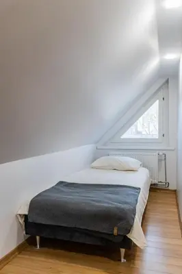 a bed in a white room with a window at Fox studio mezzanine in Šiauliai