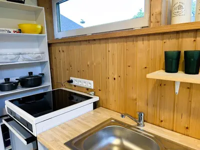 a kitchen with a sink and a stove and a window at Raimundėlio sodyba in Rokiškis