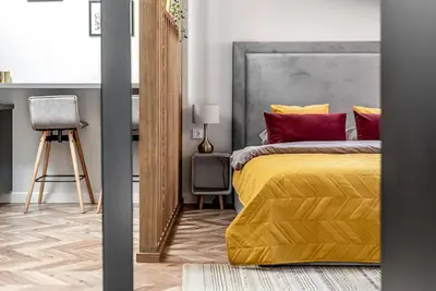 a bedroom with a yellow bed with red pillows at Studio apartment in Oldtown #F in Vilnius