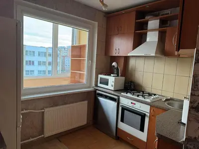 a kitchen with a stove and a microwave and a window at Spacious&cozy south apartment in Šiauliai