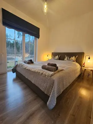 a large bed in a bedroom with a large window at Varėnės sodyba in Vėžionys