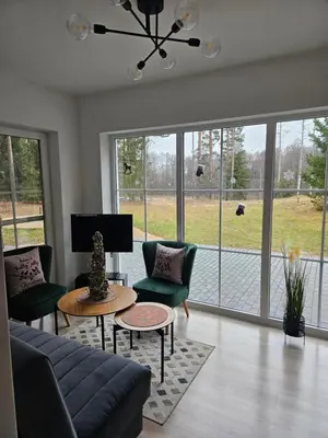 a living room with a couch and chairs and windows at Varėnės sodyba in Vėžionys