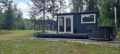 a blue tiny house with a trash can in a yard at Varėnės sodyba in Vėžionys