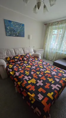 a bedroom with a bed with a colorful blanket on it at Kristi Apartments in Visaginas