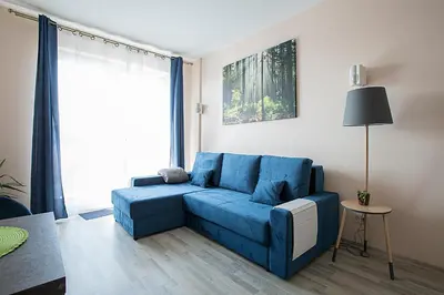 a blue couch in a living room with a window at Vita apartment in Vilnius