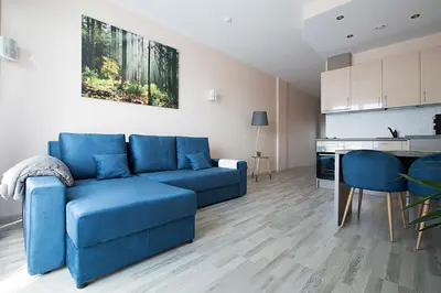 a living room with a blue couch and a kitchen at Vita apartment in Vilnius