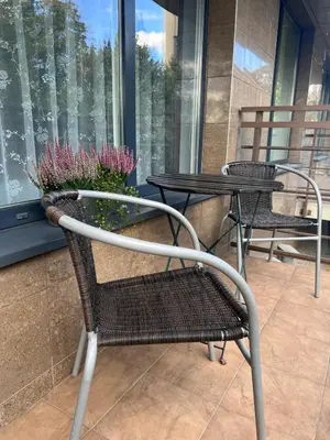 two chairs and a table with flowers on a balcony at Welcome apartment in Druskininkai