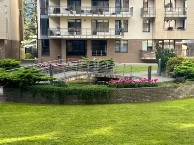 a building with a bridge and flowers in front of it at Welcome apartment in Druskininkai