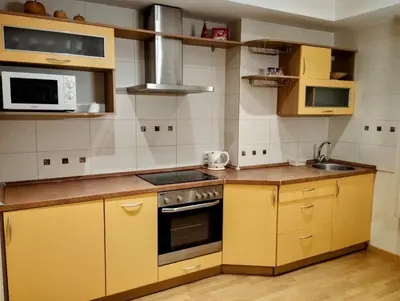 a kitchen with yellow cabinets and a stove at Welcome apartment in Druskininkai