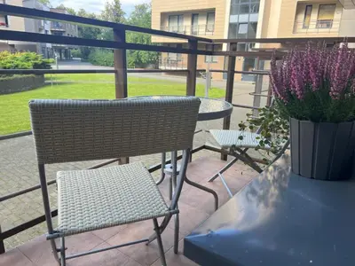a patio with two chairs and a table and a vase of flowers at Welcome apartment in Druskininkai