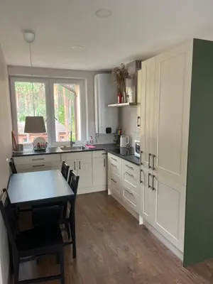 a kitchen with white cabinets and a table with chairs at Apartment 4 Palūšė in Palūšė