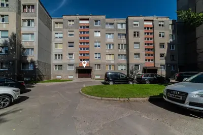 a parking lot with cars parked in front of a building at Amber Apartments in Šiauliai