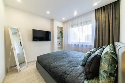 a bedroom with a bed and a flat screen tv at Amber Apartments in Šiauliai